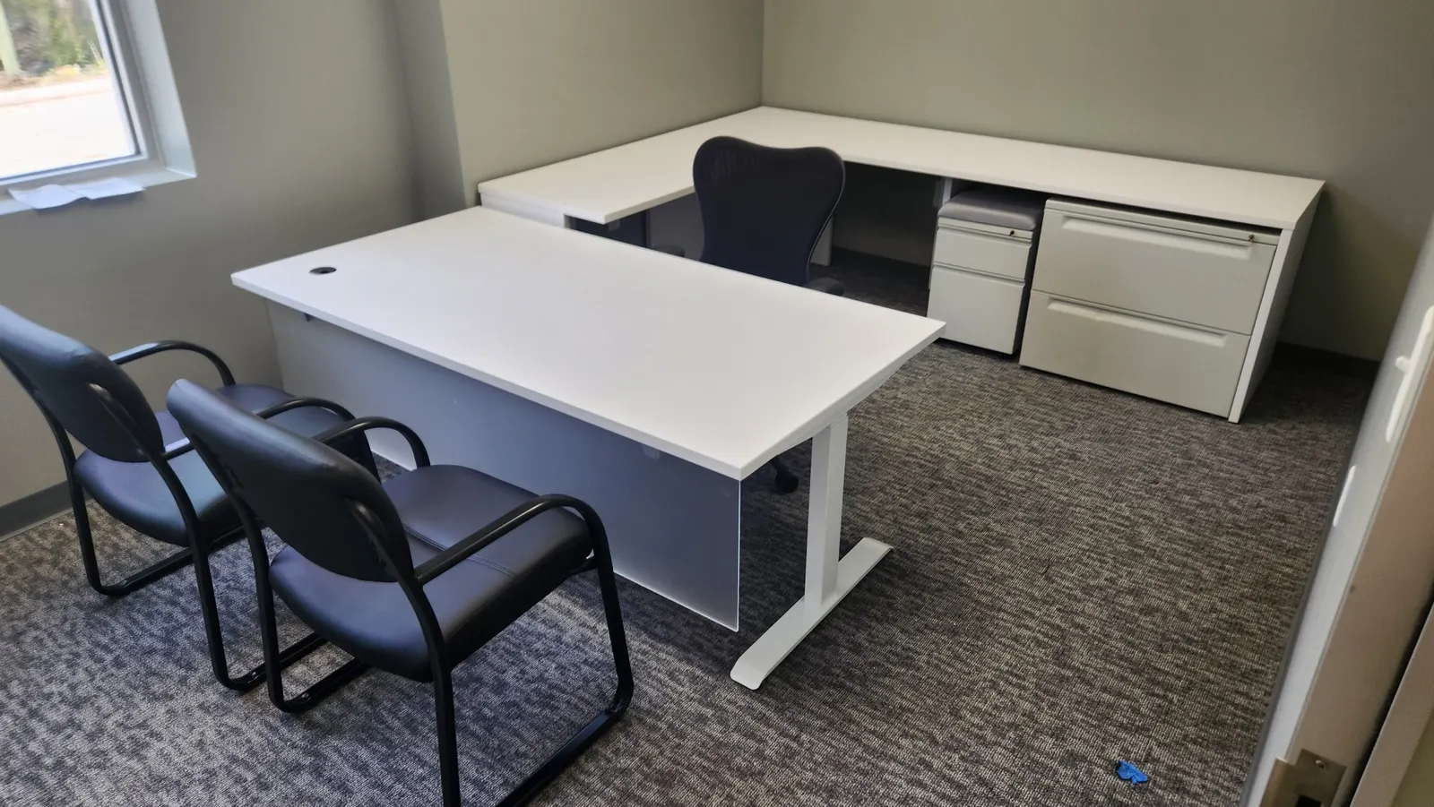 New white height-adjustable desk with lateral file and overhead storage in a private office